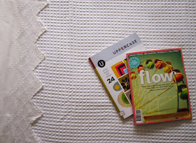 Close up of a freshly-made bed with a white waffle-weave blanket and a copy of Flow magazine and Uppercase magazine on it.