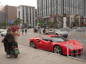 man on scooter selling candied fruit next to a red Ferrari