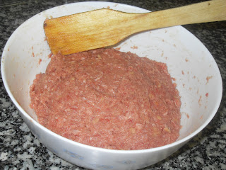 Masa de carne en un bol preparada con el huevo, las especias y las hierbas