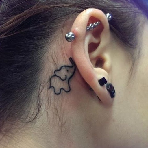 Um estilo cartoon elefante ilustrado na tinta preta por trás do portador da orelha direita neste tatuagem.
