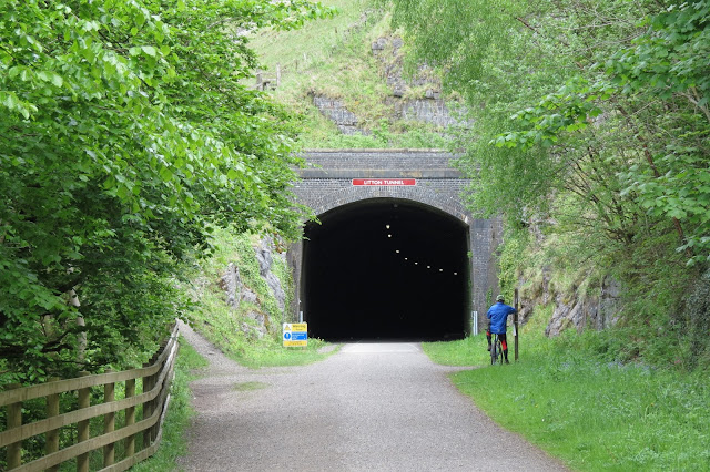 A large tunnel entrance with a cyclist leaning against a post just outside.
