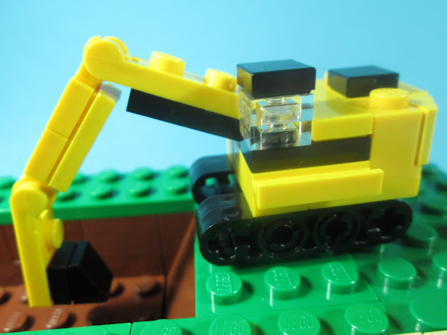 MOC LEGO - uma escavação a decorrer onde se vê uma escavadora e um camião para carregar a terra. Cena LEGO construída em micro escala.