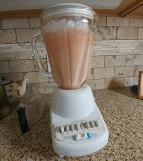 blender on a counter with the ingredients for frosé in it