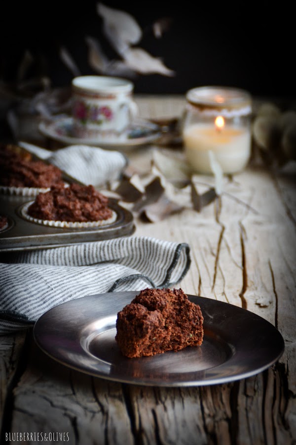 Bandeja metálica retro de muffins, paño cocina de lino gris,plato y taza de cerámica para café, fondo oscuro, luz de vela, ramas secas eucalipto