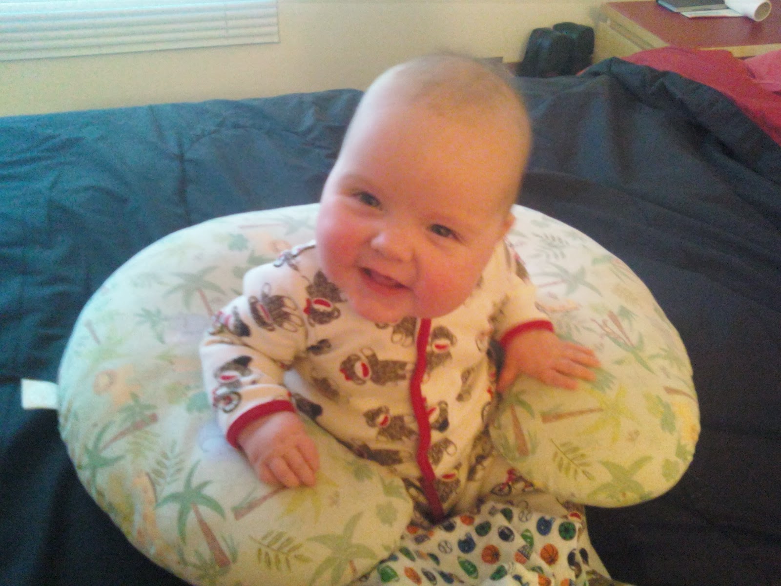baby boy in sock monkey jammies smiling and sitting up with boppy support