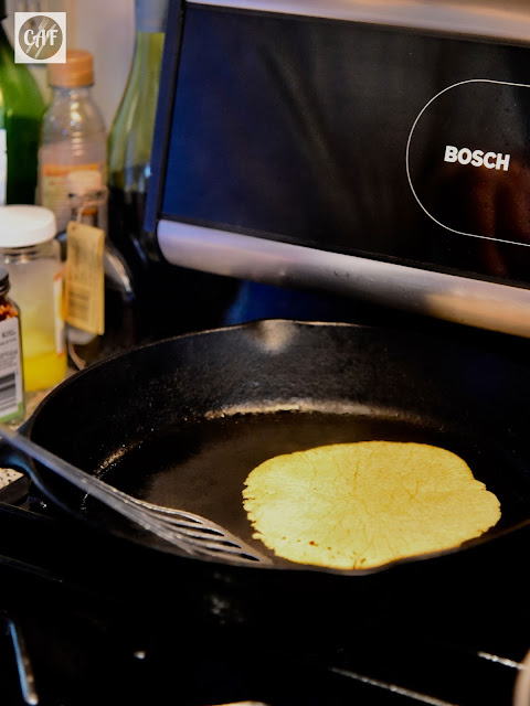 Cooking a homemade corn tortilla in a cast iron skillet on the stove