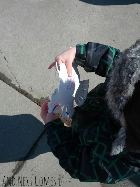 Child going on a letter walk and outdoor alphabet scavenger hunt, holding a paper plate covered in letters
