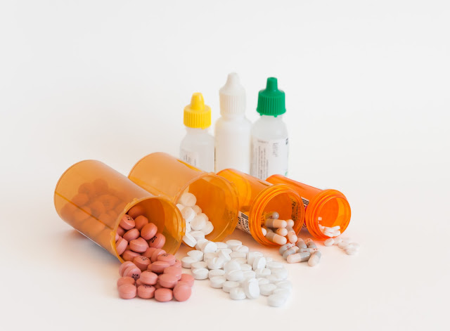 Medication containers with pills and bottles of eyedrops.