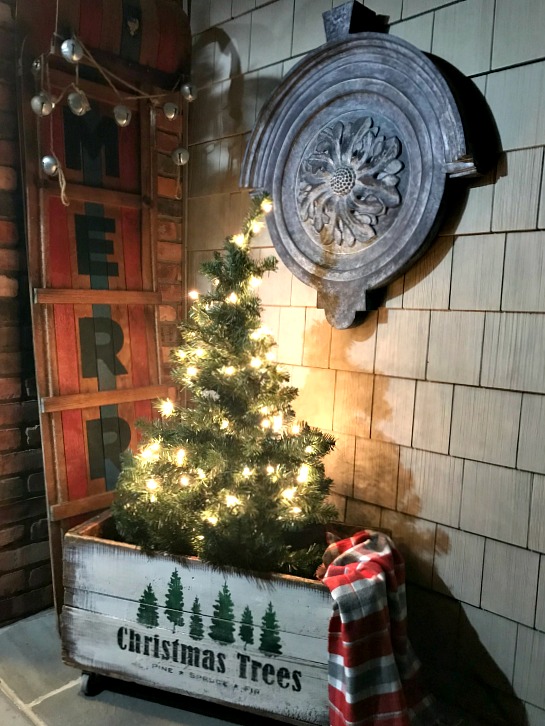 Lit tree in stenciled crate on porch