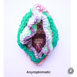 Image description: one crochet genital of blue hues is pictured on a white background. It looks rather unassuming, to represent asymptomatic STIs.