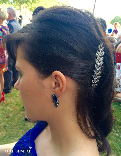 Invitada boda con peina tocado de hojas plateadas, su peinado es el pelo suelto moreno y ladeado, vestido azul klein lentejuelas