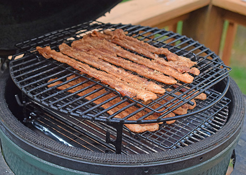 Using an adjustable rig on a Big Green Egg to make candied bacon on a kamado grill.