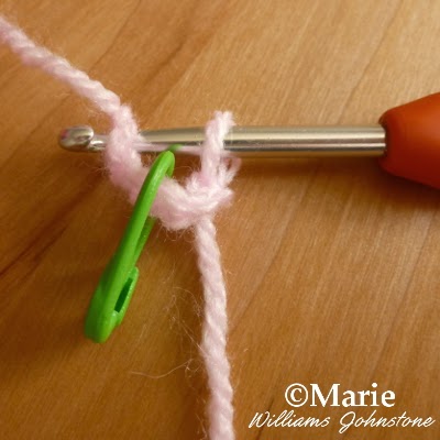 Crochet hook with short chain of yarn stitches and green stitch marker