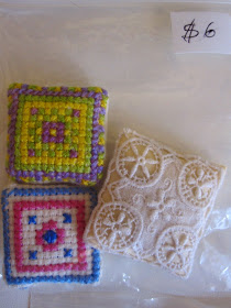 Bag with three dolls' house miniature cushions, two cross stitched, one is lace. Bag is priced at $6.