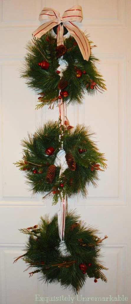 Triple Christmas evergreen wreath with candy cane ribbon on the door