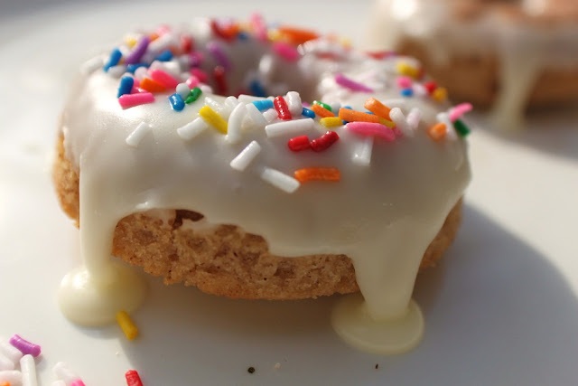 this is a baked vanilla donuts with white chocolate ganache and sprinkles on top