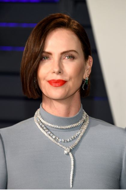Anche Charlize Theron indossa gli iconici gioielli Bulgari collezione “Serpenti”. In primo piano il collier di questa linea con diamanti, intervallato da un’enorme collier tennis in oro con diamanti molto grandi. Gli orecchini pendenti montano diamanti, smeraldi e zaffiri rettangolari degradè.
