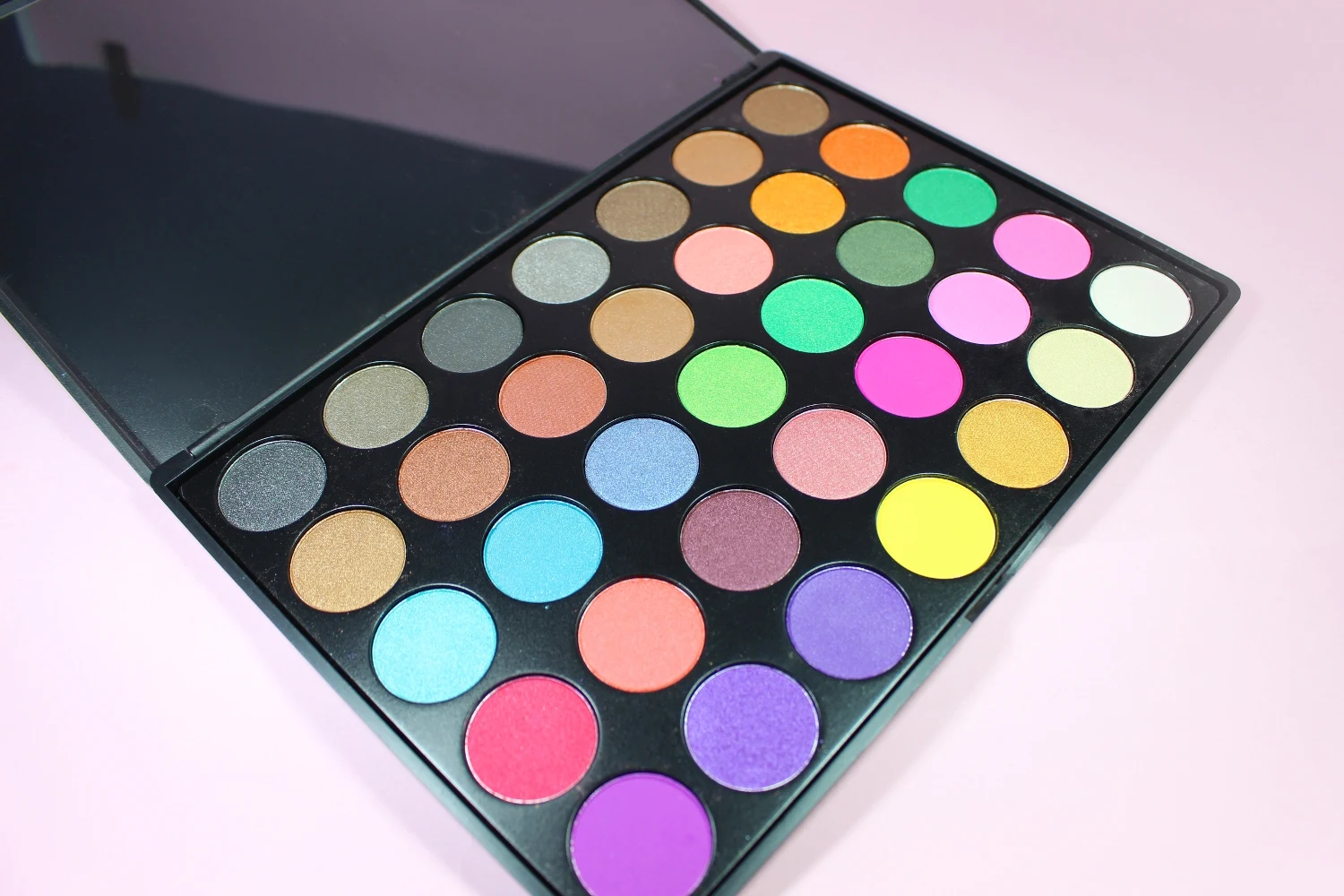 close-up studio picture of colorful eyeshadow palette on a pink background