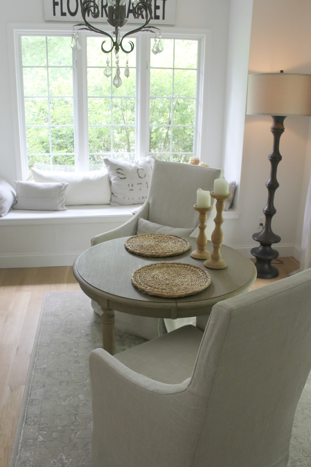 Hello Lovely's renovated kitchen breakfast nook with round dining table, floor lamp, and window seat. Walls are BM OC-151.