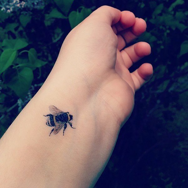 chica con tatuaje de abeja en el antebrazo