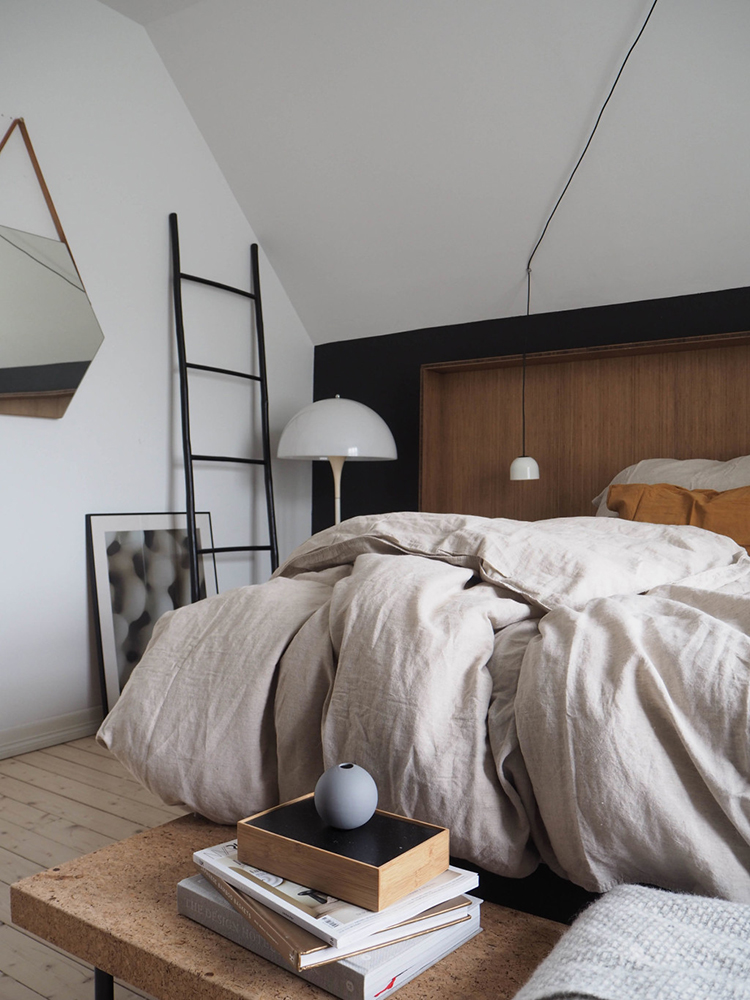 Scandinavian bedroom with black wall and wooden headboard via Only Deco Love