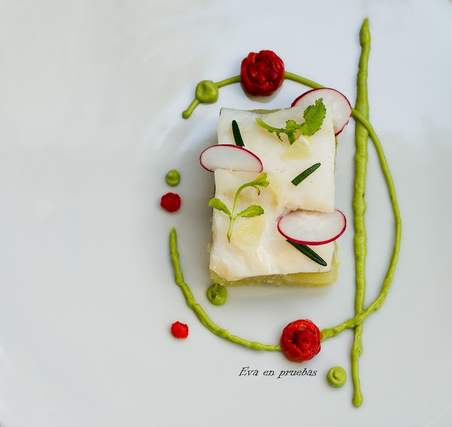 Filete de bacalao al vapor, sobre lamina cuadrada de patata al micro, decorado con un circulo de crema de aguacate y gotas de salsa de piemiento.