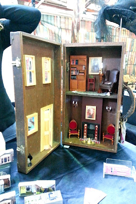 Dolls' house in a suitcase on a market stall.