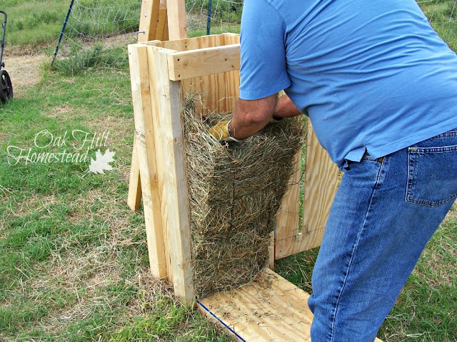 A man removing a bale of hay from the manual hay baler