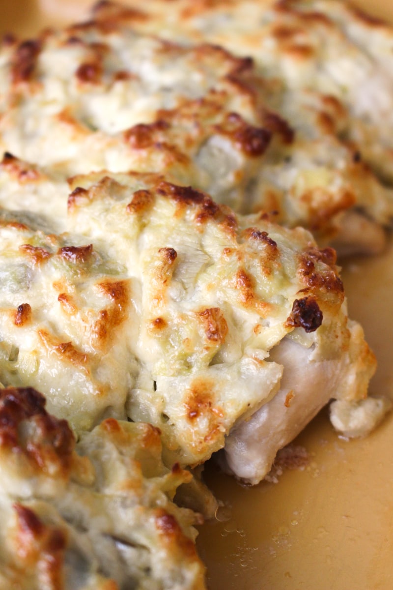 This Artichoke Chicken Bake features juicy baked chicken smothered in a creamy parmesan and artichoke topping. It is an easy dinner recipe that you will want to make again and again! #chickenrecipe #artichokes #easydinner 