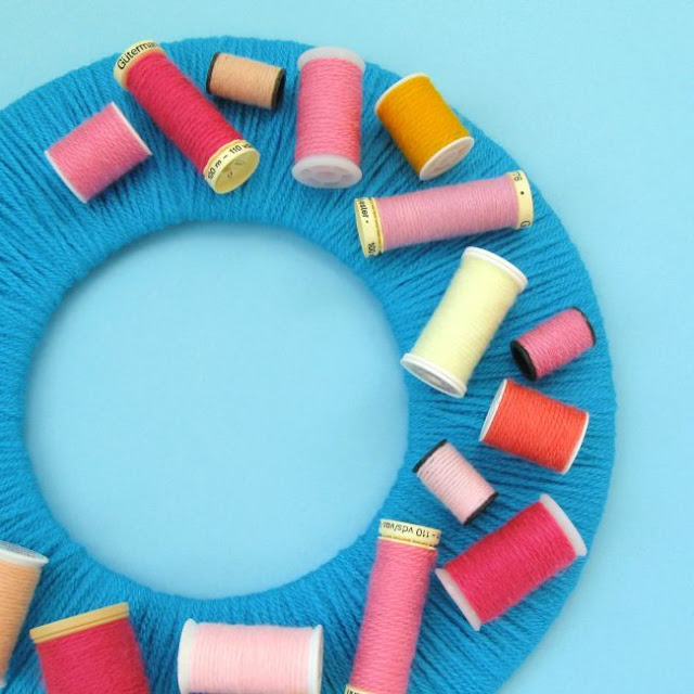 DIY Upcycled Sewing Thread Reels Wreath Tutorial Colourful yarn-wrapped wreath decorated with upcycled sewing reels