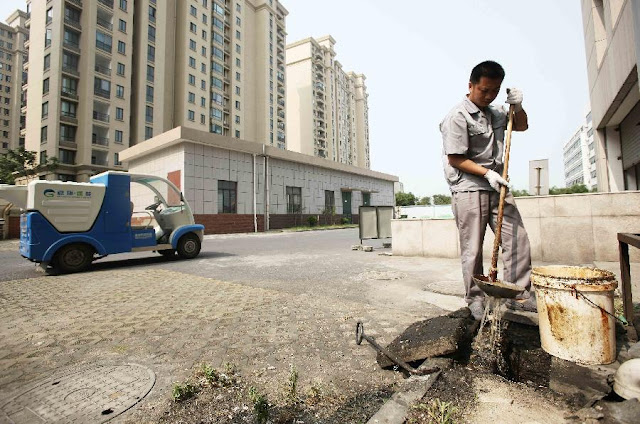 Man extracting gutter oil from the sewer
