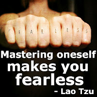 Outstretched fists with fear less tattooed on them with quote by Lao Tzu, Mastering oneself makes you fearless.