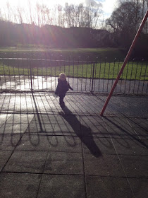 Toddler with sun behind him in park, casting shadows