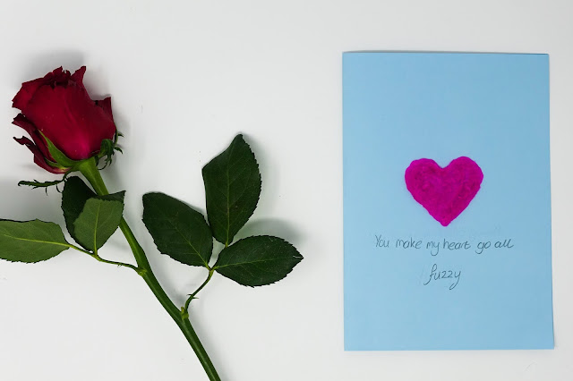 red rose and a blue card with a pink heart and message