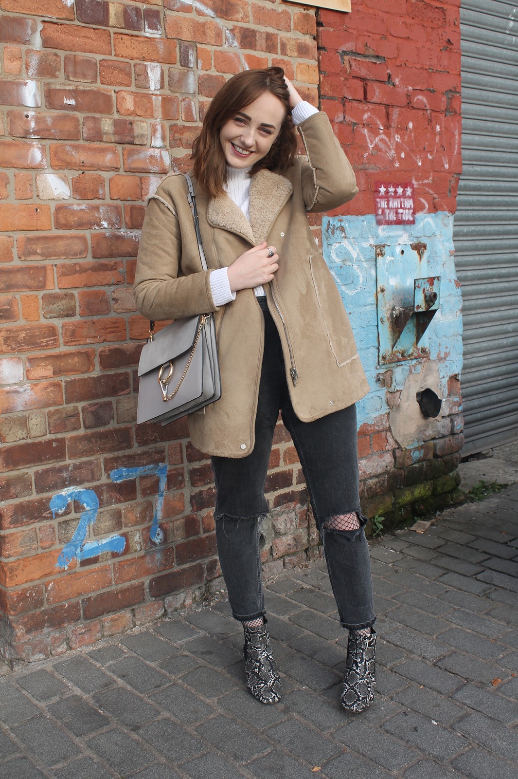 tan faux sheepskin coat from Pull & Bear, white rib roll neck jumper from ASOS, Chloe faye bag in grey copy, ASOS furlough jeans in washed black with busted knees over fishnet tights,  ASOS amber snake boots