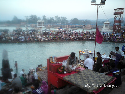 Priests sitting on raised wooden planks at the Har Ki Pauri Ghat, Haridwar