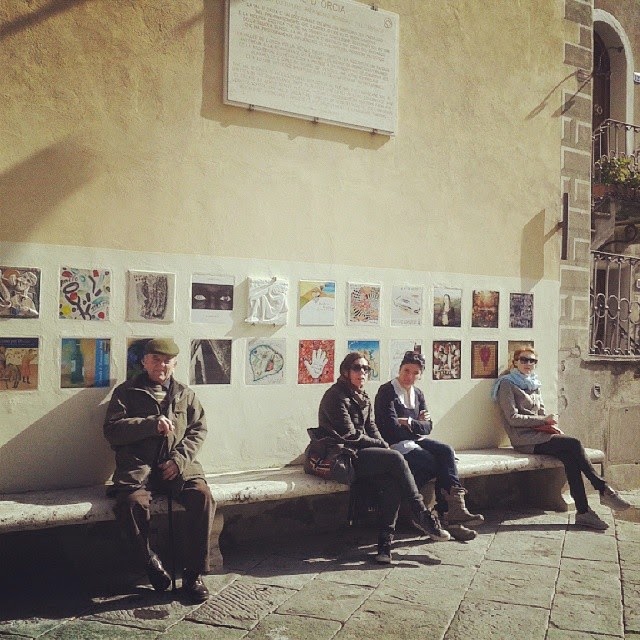 Locals enjoying the sunshine on a long stone bench under the Brunello vintage tiles 