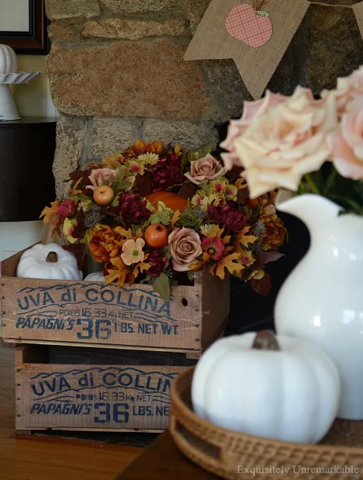 Two stained grape crates filled with faux pumpkins and flowers