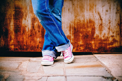 bottom half of legs in torn jeans and tennis shoes