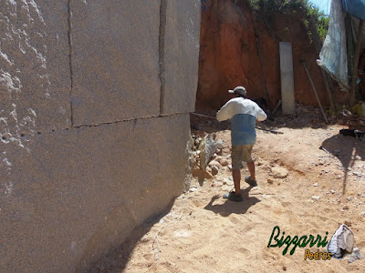 Pedra de granito bruto sendo cortada para execução de pedra paralelepípedo.
