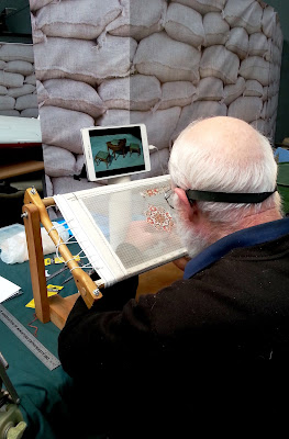 A man stitching a very fine miniature carpet.