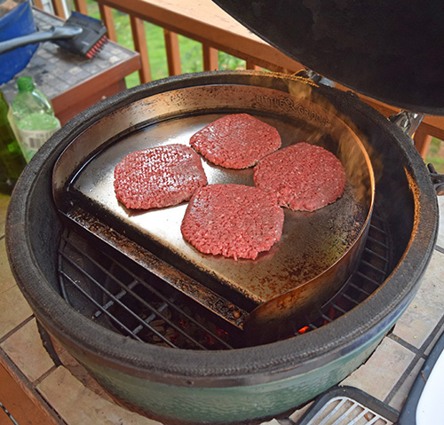 Cooking Smash Steak Burgers on a griddle accessory on a Big Green Egg kamado grill. #BestBeef #NationalBurgerMonth