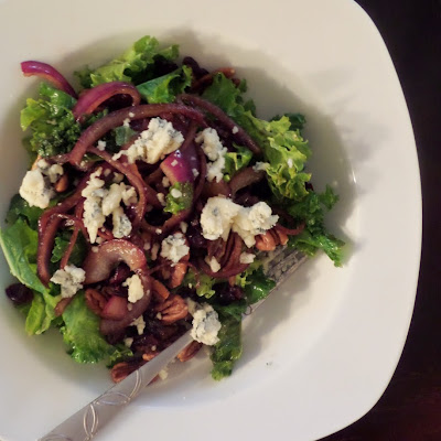 Warm Kale Salad:  A salad made of red onions sauteed in oil and balsamic vinegar mixed with kale and topped with blue cheese, toasted pecans, and dried cranberries.