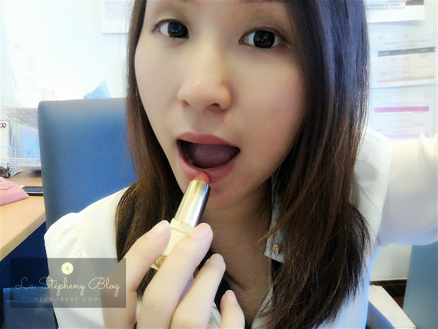 A,n asian chinese girl applying the YSL nude color lisptick to her lips