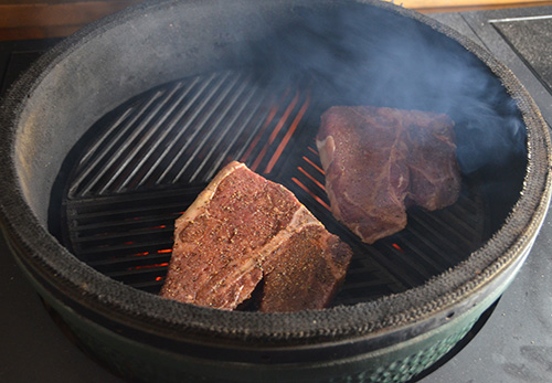 Grilling porterhouse steaks on a Big Green Egg kamado grill with craycort cast iron grates and a kick ash basket.
