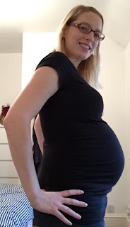 Me standing sideways wearing black showing my pregnant belly