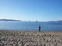 A solitary person facing the wide open waters of English Bay in Vancouver