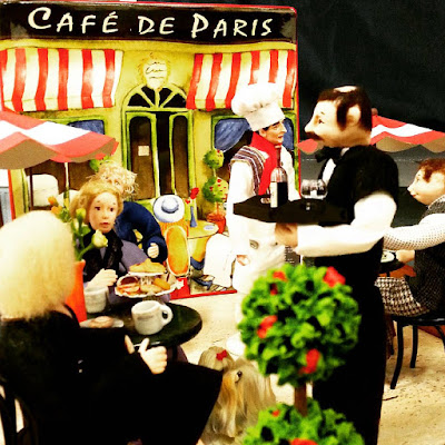 One-twelfth scale miniature french cafe scene with diners outdoors under umbrellas.