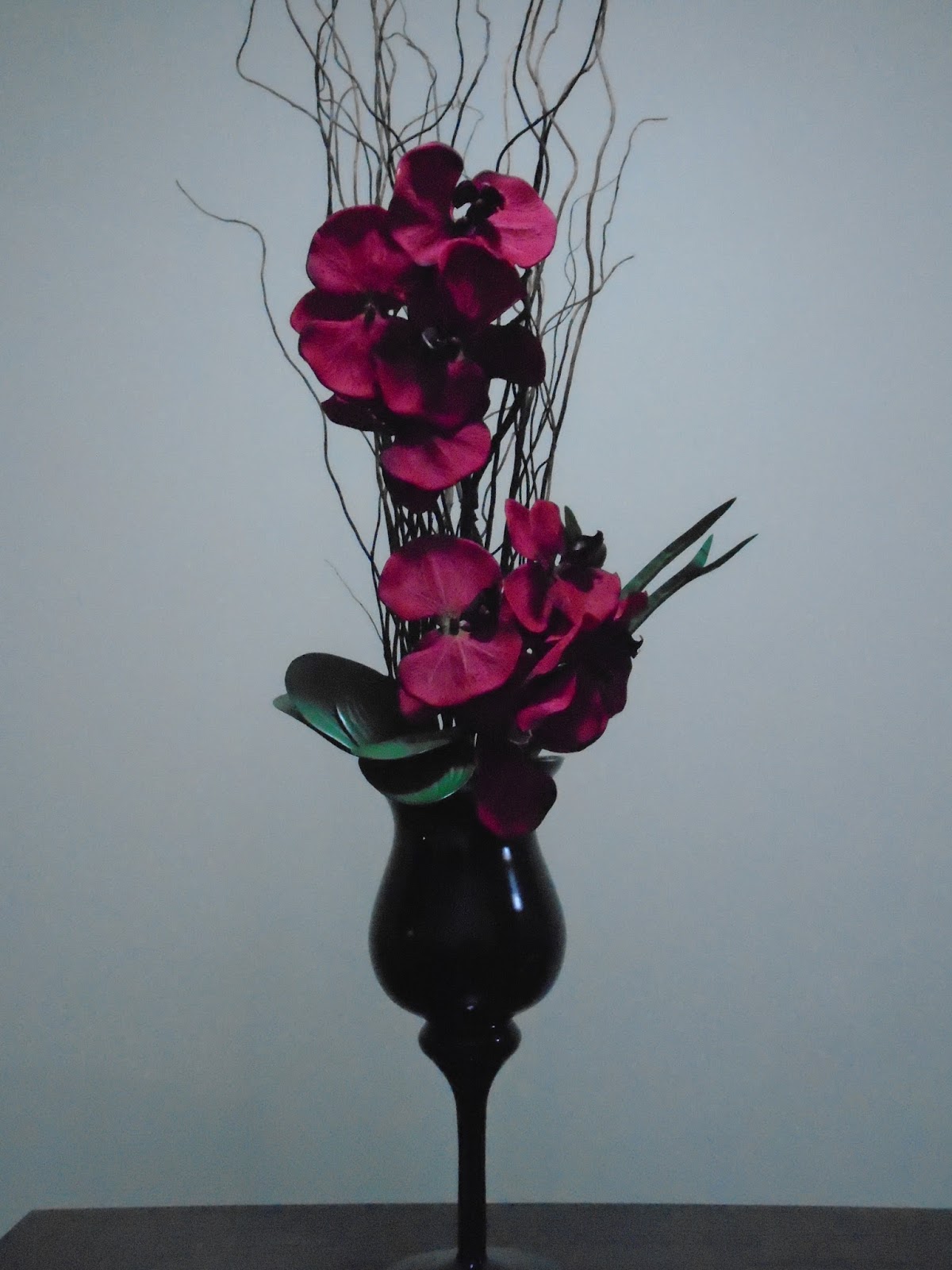 Samara Flores: Taça preta com galhos secos e orquídeas vermelhas