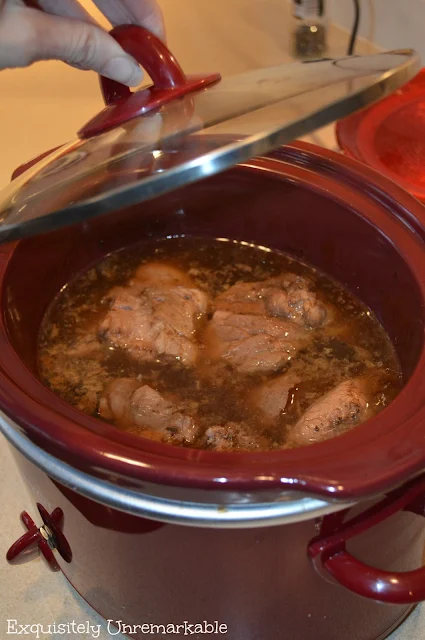 Slow Cooker top open to expose pork cooking inside